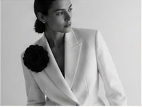 Black-and-white tailored portrait with floral lapel detail.